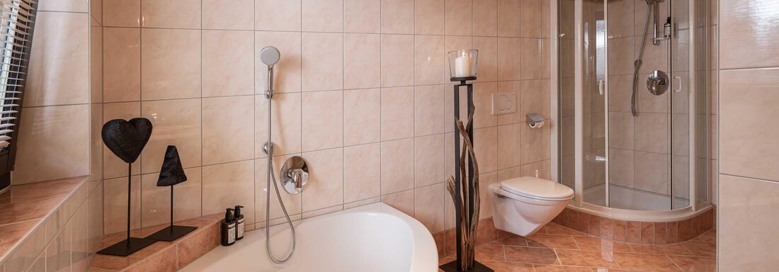 Ein modernes Badezimmer mit einer Badewanne und einer Dusche. Die Wände sind gefliest und die Einrichtung ist stilvoll und elegant. - Apart Reinstadler - Sölden