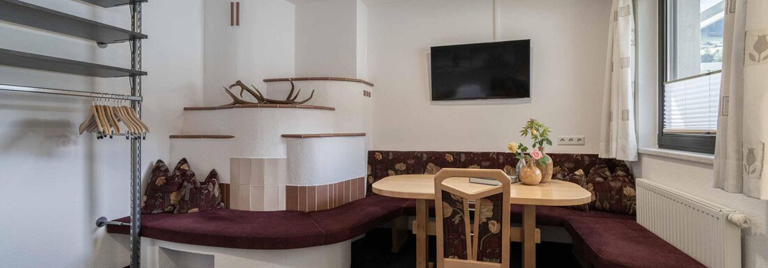 Ein gemütlicher Essbereich mit einem runden Tisch und einer gemütlichen Sitzbank. An der Wand hängt ein Fernseher, und die Einrichtung ist modern und funktional. - Apart Reinstadler - Sölden