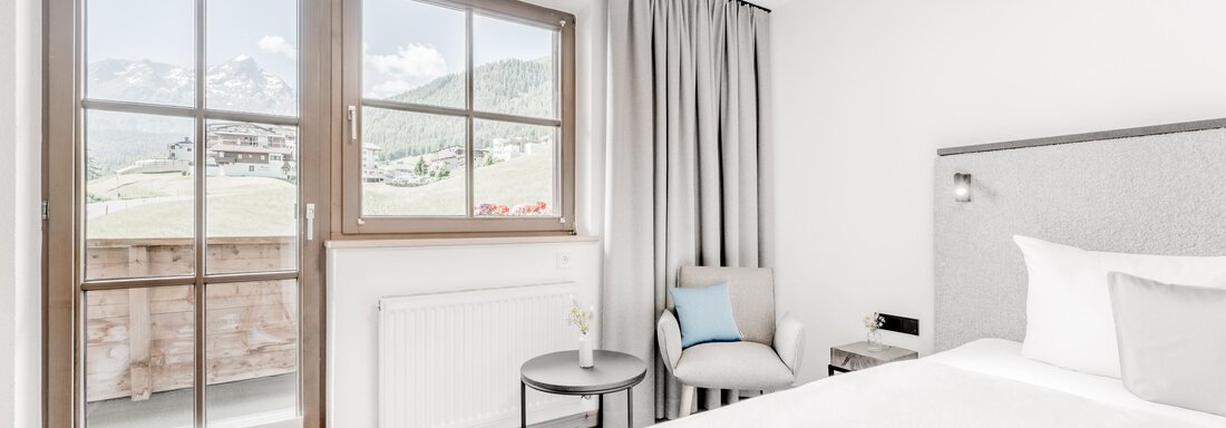Ein modernes Schlafzimmer mit einem großen Fenster und Aussicht auf die Berge. Der Raum ist hell und minimalistisch eingerichtet. - Appartement Montanara - Sölden