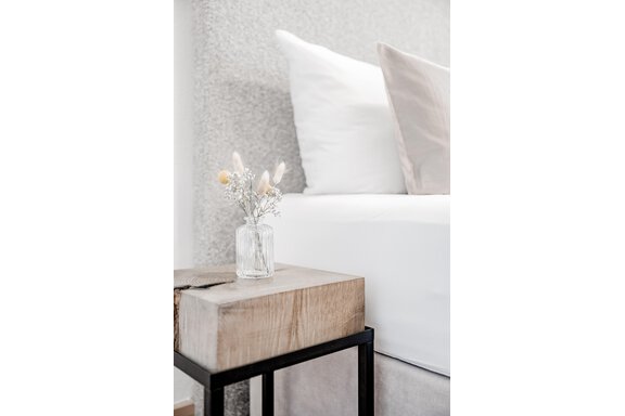 Ein gemütliches Schlafzimmer mit einem Bett und einem Holztisch. Auf dem Tisch steht eine kleine Vase mit Trockenblumen. - Appartement Montanara - Sölden