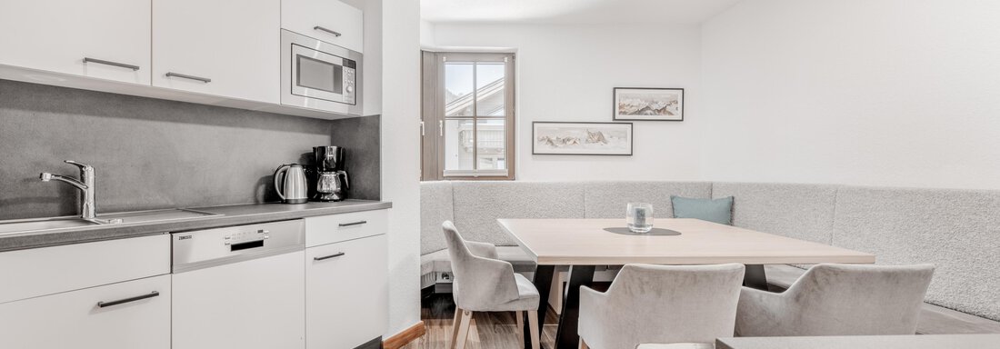 Moderne Küche mit einem großen Esstisch und hellen Möbeln. Ein Fenster sorgt für viel Tageslicht. - Appartement Montanara - Sölden