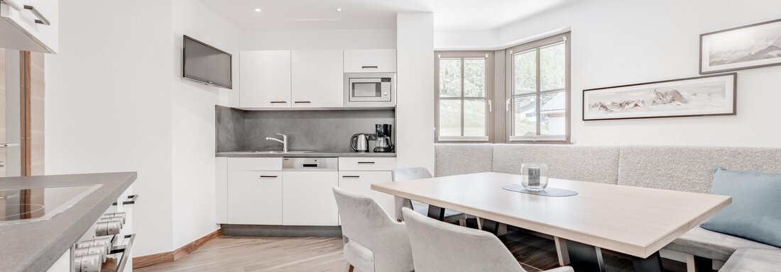 Eine moderne Küche mit einem Essbereich und großen Fenstern. Der Raum ist hell und freundlich gestaltet. - Appartement Montanara - Sölden