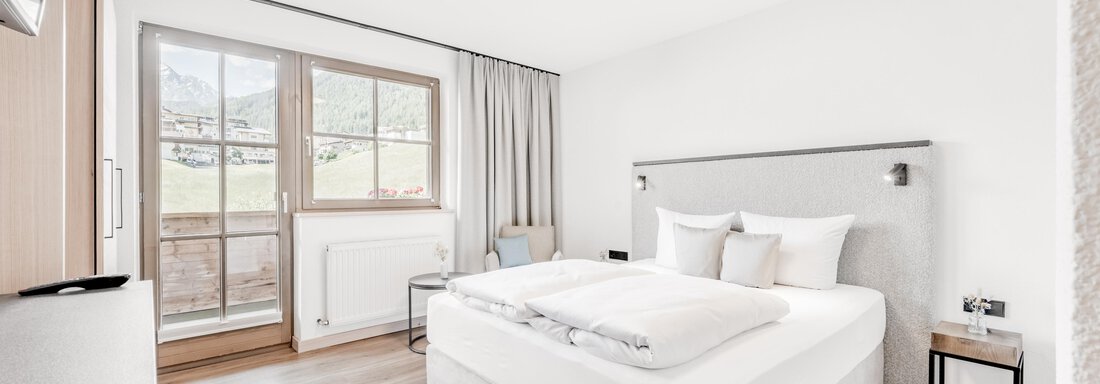 Ein modernes Schlafzimmer mit einem großen Bett und hellen Wänden. Das Zimmer hat Fenster mit Aussicht und minimalistischer Einrichtung. - Appartement Montanara - Sölden