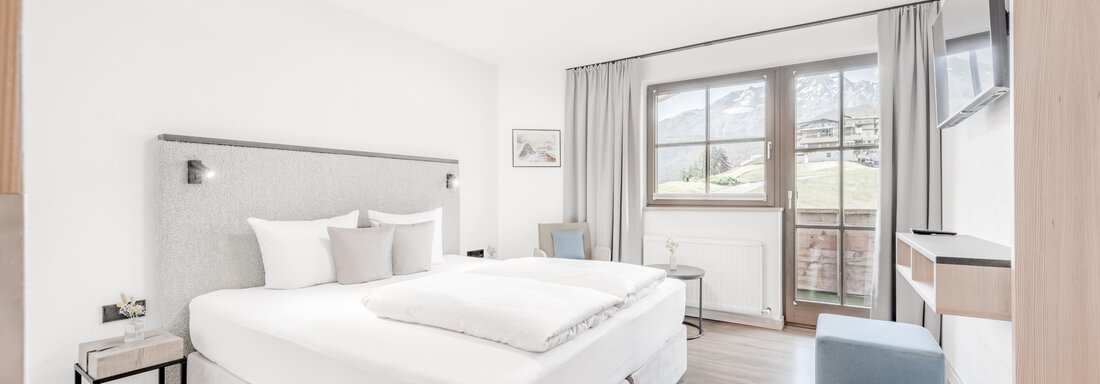 Ein modernes Schlafzimmer mit einem Doppelbett und hellem Holzfußboden. Große Fenster sorgen für viel Tageslicht und bieten einen schönen Ausblick. - Appartement Montanara - Sölden