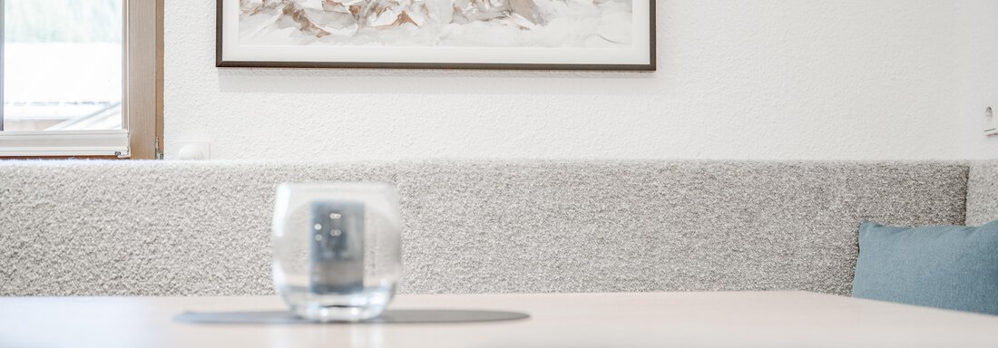 Ein modernes Wohnzimmer mit einem Tisch und einem Glas. An der Wand hängen Kunstwerke, und der Raum hat eine helle, einladende Atmosphäre. - Appartement Montanara - Sölden
