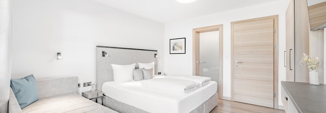 Ein modernes Schlafzimmer mit zwei Betten und einem gemütlichen Schlafsofa. Die Wände sind hell gestrichen und der Boden ist aus Holz. - Appartement Montanara - Sölden