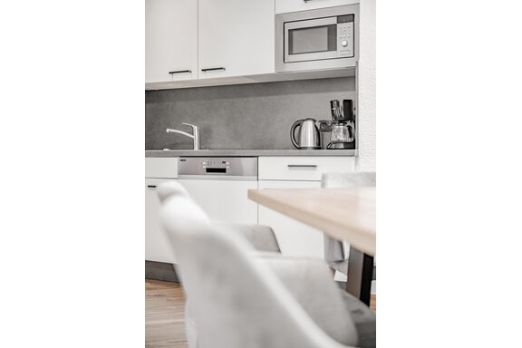Eine moderne Küche mit weißen Schränken und modernen Geräten. Die Tischfläche ist aus Holz und die Stühle sind bequem. - Appartement Montanara - Sölden