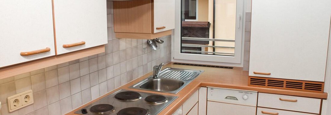 Eine moderne Küche mit Holzoberflächen und weißen Schränken. Sie verfügt über einen Herd, eine Spüle und ein Fenster mit Blick nach draußen. - Appartement Viertler - Sölden