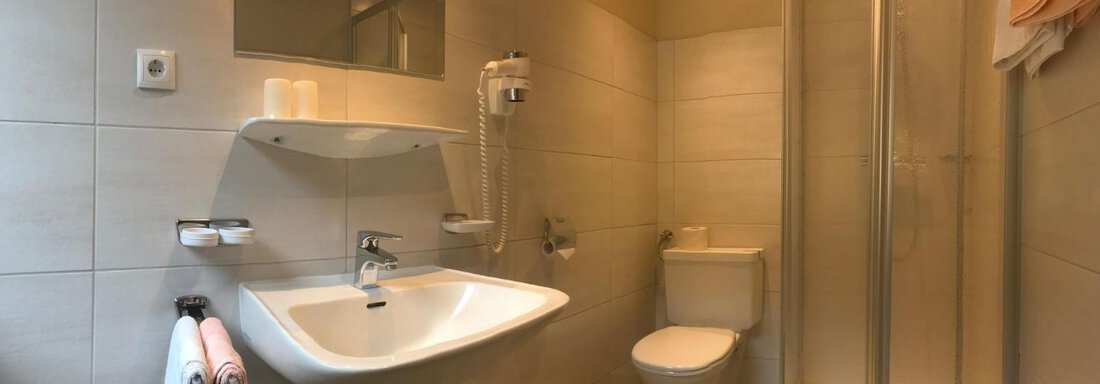 Ein modernes Badezimmer mit Dusche, Waschbecken und Toilette. Die Wände sind hell gefliest und es gibt Handtücher sowie Pflegeartikel. - Appartement Viertler - Sölden