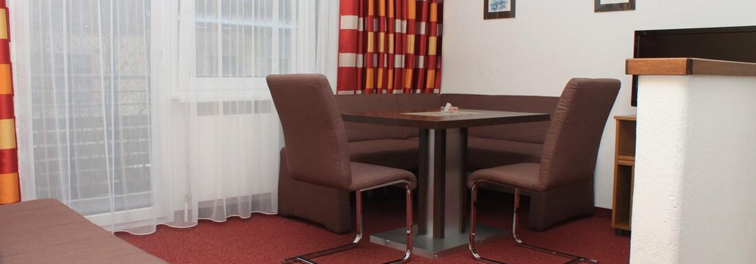 Ein gemütlicher Essbereich mit einem Tisch und Stühlen. Der Raum hat helle Vorhänge und eine freundliche Farbgestaltung. - Appartement Viertler - Sölden