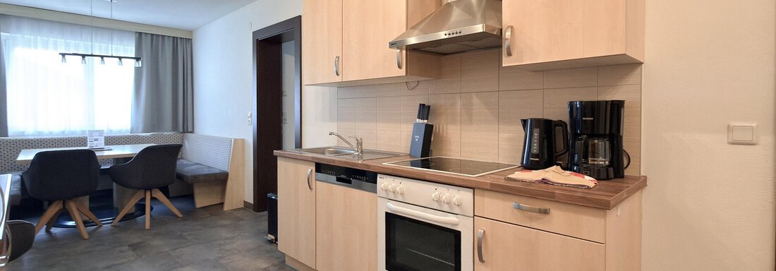 A modern kitchen with light wood cabinets and appliances. The room is spacious and well-lit. - Appartementhaus A CASA "Kristall" - Sölden