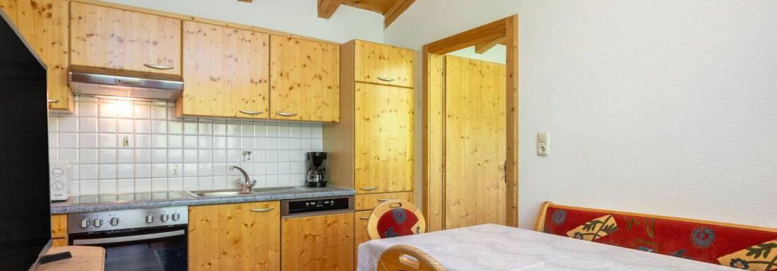 Eine helle Küche mit Holzmöbeln und einem Esstisch. Der Raum hat eine gemütliche Atmosphäre und ist gut ausgestattet. - Garni Nadine - Sölden