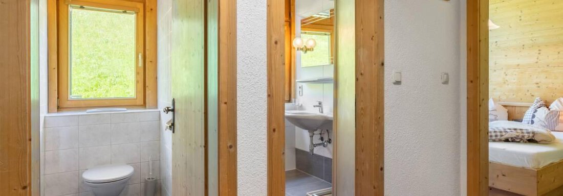Ein heller Flur mit Holzdetails und Fenster. Auf der linken Seite befindet sich ein Badezimmer und auf der rechten Seite ein Schlafzimmer. - Garni Nadine - Sölden