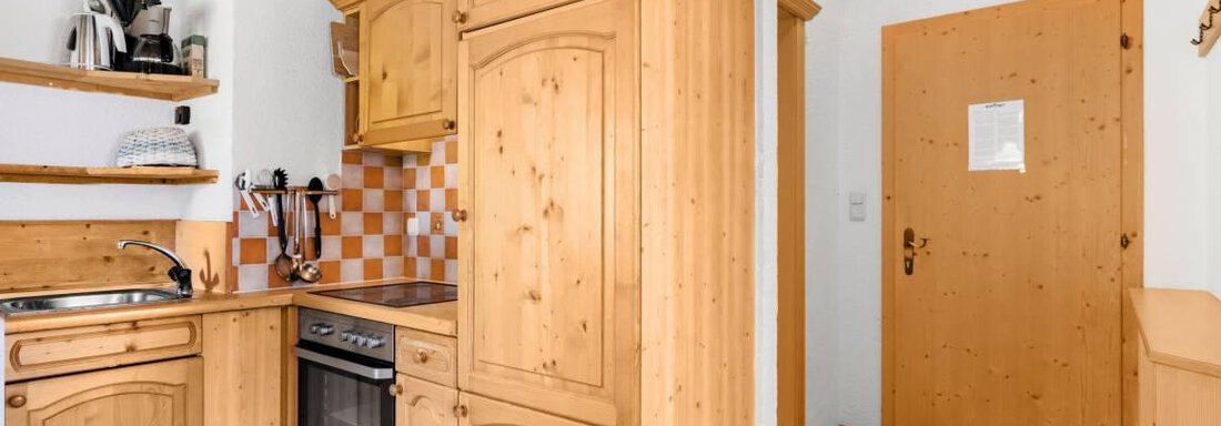 Eine gemütliche Küche mit Holzmöbeln und einem modernen Küchenequipment. Der Boden ist aus Holz und die Wände sind hell gestaltet. - Garni Nadine - Sölden