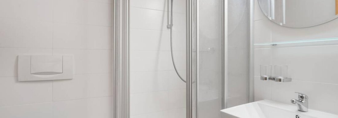 Ein modernes Badezimmer mit einer Dusche und einem Waschbecken. Der Boden hat ein einzigartiges Design mit einem Geweihmotiv. - Garni Nadine - Sölden