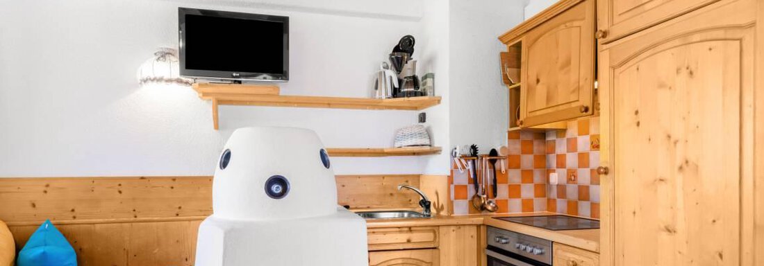Eine moderne Küche mit Holzschränken und einem hellen, freundlichen Design. Die Sitzecke ist mit farbigen Kissen dekoriert und bietet eine gemütliche Atmosphäre. - Garni Nadine - Sölden