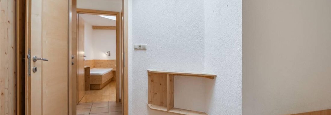 Ein einfaches Zimmer mit Holzfußboden und zwei Betten. Die offene Tür im Hintergrund führt zu einem weiteren Raum. - Garni Nadine - Sölden