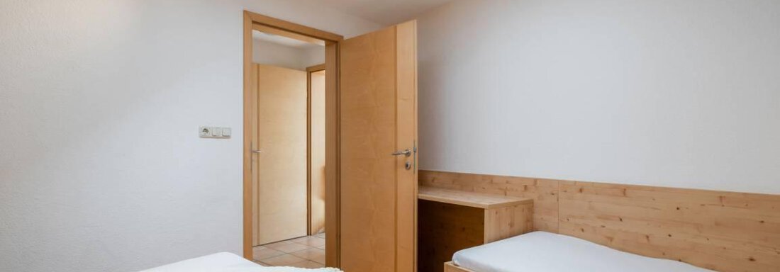 Ein einfaches Schlafzimmer mit zwei Betten und einem hellen Holzdekor. Ein Dachfenster sorgt für ausreichend Tageslicht. - Garni Nadine - Sölden