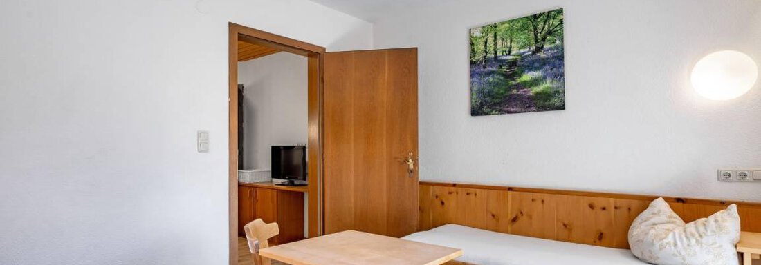Ein einfaches Zimmer mit Holzmöbeln und zwei Betten. An der Wand hängt ein Bild von einer Landschaft und ein Tisch mit Stühlen ist vorhanden. - Garni Nadine - Sölden