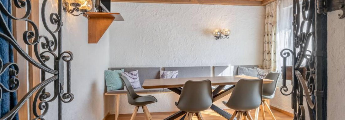 Ein modern eingerichteter Tisch mit Stühlen in einem hellen Raum. Die Wände sind in neutralen Farben gehalten, und ein Holzdach sorgt für eine gemütliche Atmosphäre. - Garni Nadine - Sölden