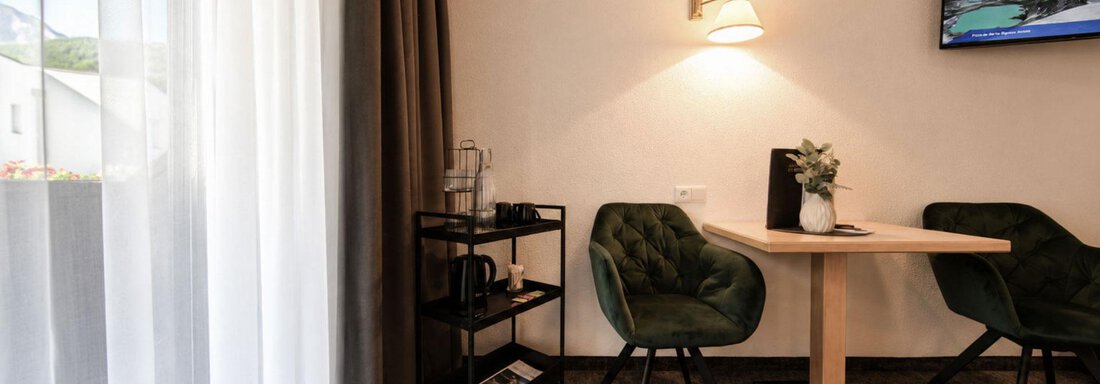 A modern room with a table and two chairs.  
On the wall, there is a television and a shelf with water. - Garni Rustica - Sölden