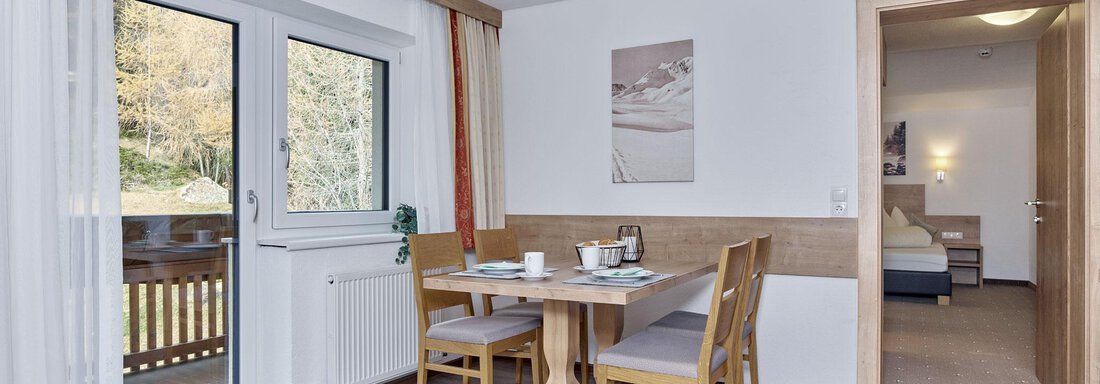 Ein gemütlicher Essbereich mit einem Tisch und Stühlen. Fenster bieten einen Blick ins Freie und die Einrichtung ist modern und freundlich. - Gästehaus Bergkristall - Sölden