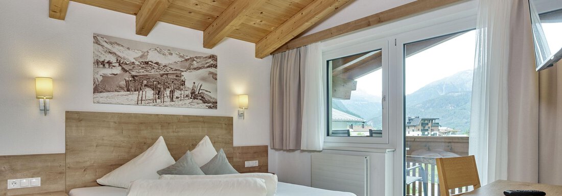 Ein modernes Schlafzimmer mit Holzdecken und großen Fenstern. Das Zimmer ist gemütlich eingerichtet und bietet einen Blick auf die umliegenden Berge. - Gästehaus Bergkristall - Sölden