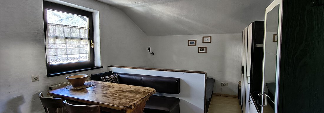 A bright dining area with a wooden table and chairs. There is a cozy seating corner and a large window for plenty of daylight. - Gästehaus Hermann Arnold - Sölden