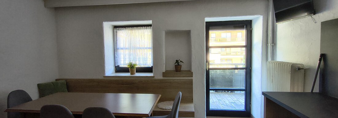 A modern furnished dining area with a table and chairs. Large windows let in a lot of light into the room. - Gästehaus Hermann Arnold - Sölden
