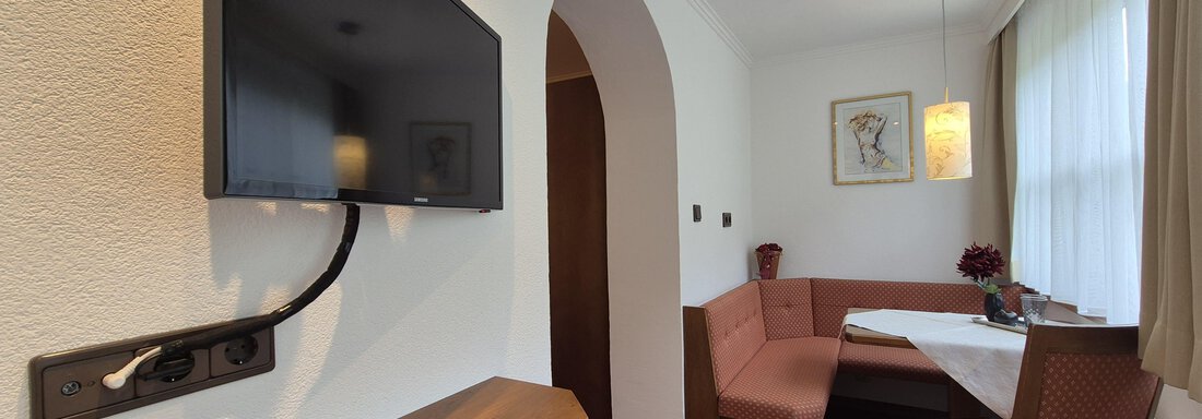Lichtdurchfluteter Raum mit Sitzecke, Fernseher und Garderobe. - Gästehaus Maier - Sölden