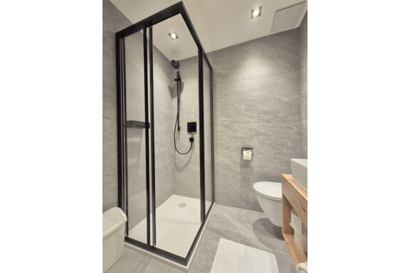 Ein modernes Badezimmer mit einer Dusche. Der Raum hat helle Fliesen und einen großen Spiegel. - Gästehaus Maier - Sölden