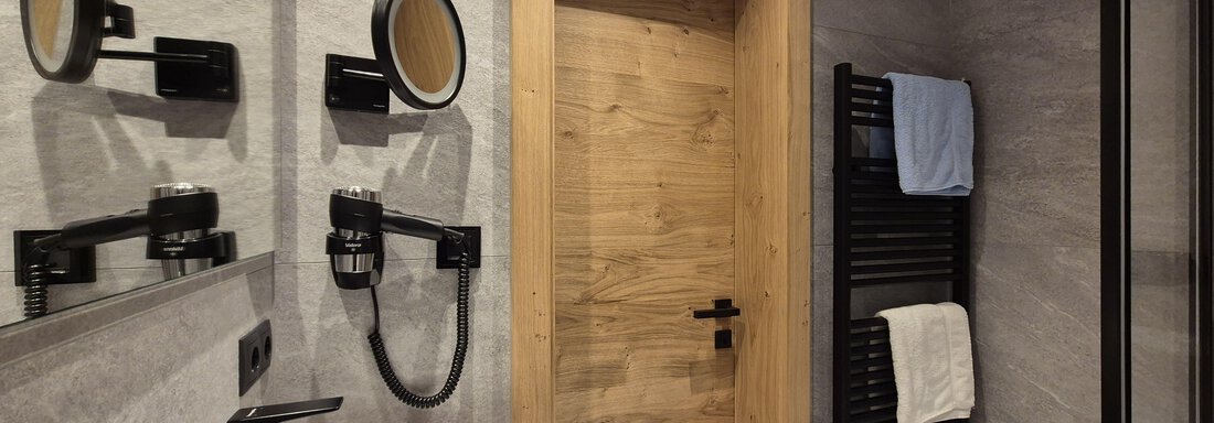 Ein modernes Badezimmer mit einer Dusche. Der Raum hat helle Fliesen und einen großen Spiegel. - Gästehaus Maier - Sölden