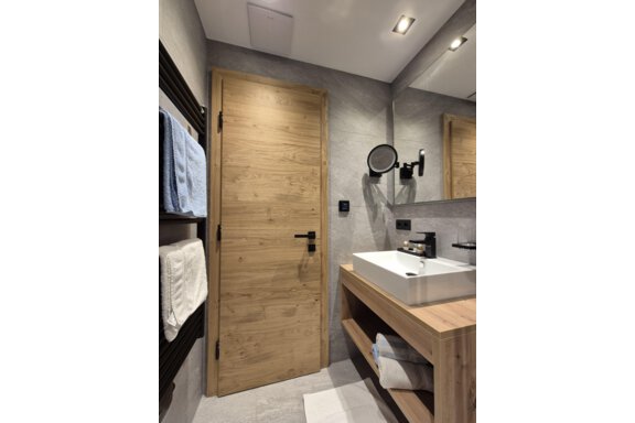 Ein modernes Badezimmer mit einer Dusche. Der Raum hat helle Fliesen und einen großen Spiegel. - Gästehaus Maier - Sölden