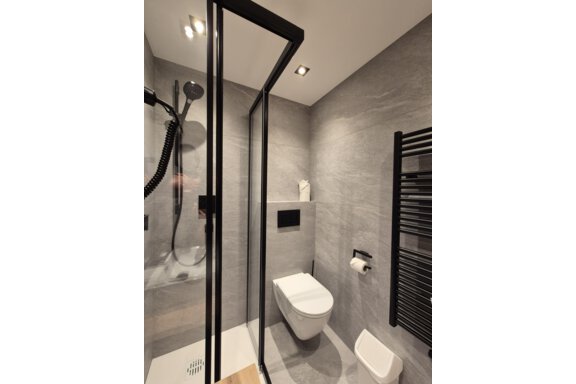Ein modernes Badezimmer mit einer Dusche. Der Raum hat helle Fliesen und einen großen Spiegel. - Gästehaus Maier - Sölden