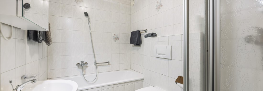 Ein modernes Badezimmer mit einer Dusche, Badewanne und Waschbecken. Die Wände sind gefliest und es gibt Holzverkleidungen an der Decke. - Gasthof Granstein - Sölden