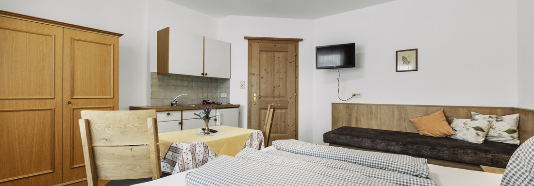 Ein gemütliches Zimmer mit zwei Betten, einer kleinen Küche und einem Fernseher. Die Einrichtung ist funktional und hell, mit Holzdetails und einer einladenden Atmosphäre. - Gasthof Granstein - Sölden