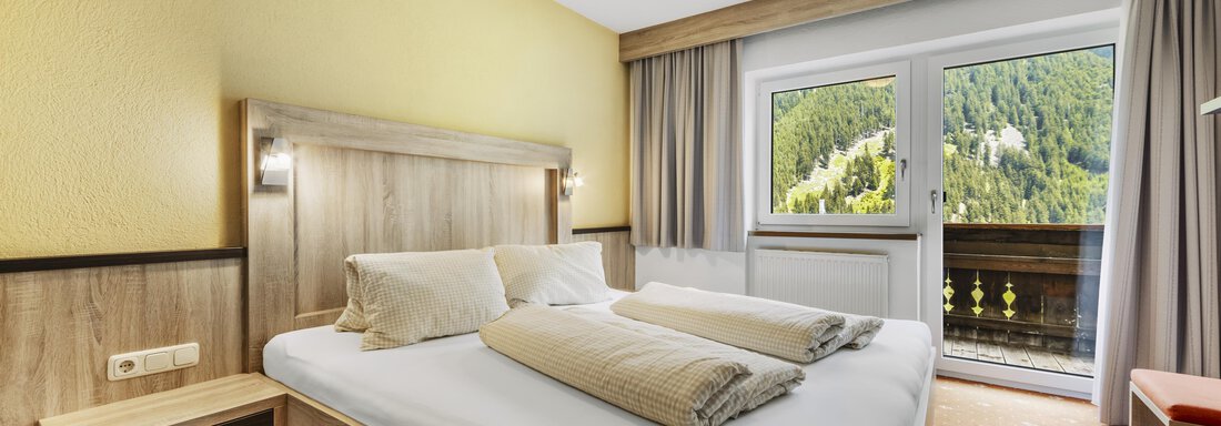 _F0A8113 Ein gemütliches Schlafzimmer mit einem Doppelbett und zwei Kissen. Durch die Fenster hat man einen schönen Blick auf die umliegenden Berge. - Gasthof Granstein - Sölden