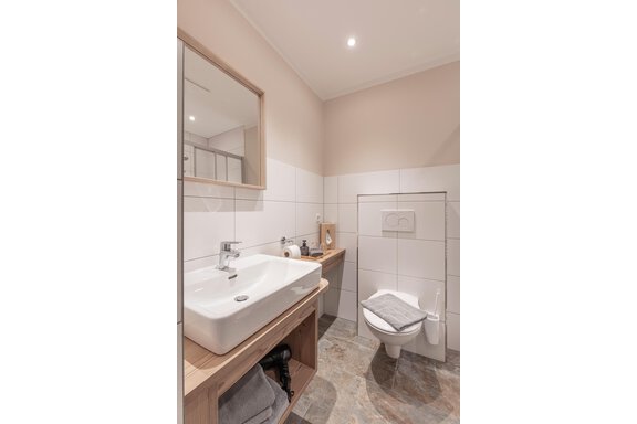 A modern bathroom with a sleek sink and an elegant toilet. The decor is bright and designed in a minimalist style. - GIGGI Tenne Studios - Sölden