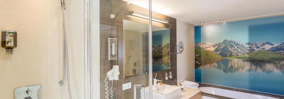 A modern bathroom with a shower and a wooden vanity. In the background, a beautiful mountain picture is visible. - Glanz & Glory Hotel - Sölden