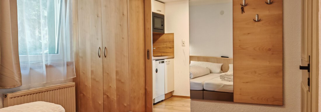 Schlafzimmer A Ein gemütliches Schlafzimmer mit einem Doppelbett und Holzmöbeln. Das Zimmer hat ein Fenster mit Vorhängen und einen Fernseher an der Wand. - Haus der Bergfreunde - Sölden