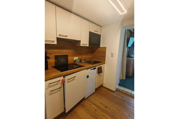 Eine moderne Küche mit Holzverkleidung und einer schwarzen Kochfläche. Sie ist gut ausgestattet und wirkt einladend. - Haus der Bergfreunde - Sölden