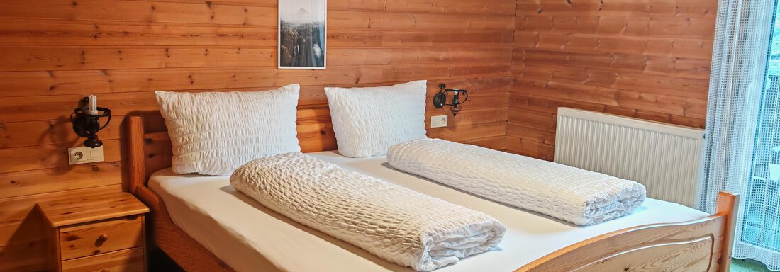 Ein gemütliches Schlafzimmer mit Holzverkleidung und zwei Einzelbetten. Das Zimmer ist einfach eingerichtet und hat warme, einladende Farben. - Haus der Bergfreunde - Sölden
