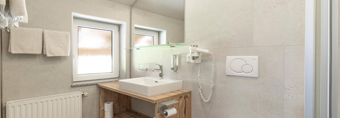 Ein modernes Badezimmer mit einer hellen und funktionalen Einrichtung. Es gibt ein Waschbecken, eine Dusche und einen Toilettenbereich. - Haus Falkner Ignaz - Sölden