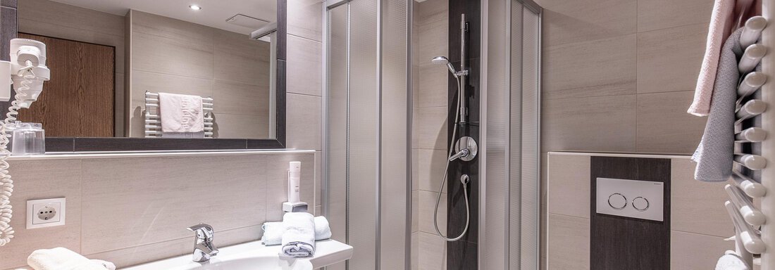 Ein modernes Badezimmer mit einer Dusche und einem Waschbecken. Die Wände sind in neutralen Farben gehalten und der Raum wirkt hell und einladend. - Haus Manfred - Sölden