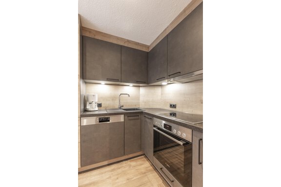 Eine moderne Küche mit grauen Schränken und Edelstahl-Geräten. Sie ist gut beleuchtet und hat eine helle, einladende Atmosphäre. - Haus Manfred - Sölden