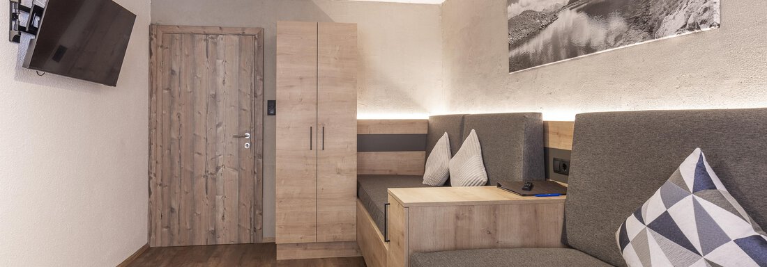 Ein modernes Zimmer mit Holzfußboden und gemütlichen Sitzgelegenheiten. An der Wand hängt ein Fernseher und ein großes Foto eines landschaftlichen Motives. - Haus Manfred - Sölden