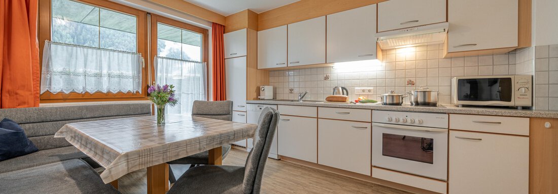 Appartement Sölden A modern kitchen with bright furniture and a dining area. The window lets in a lot of daylight and there are fresh flowers on the table. - Haus Nicola - Sölden