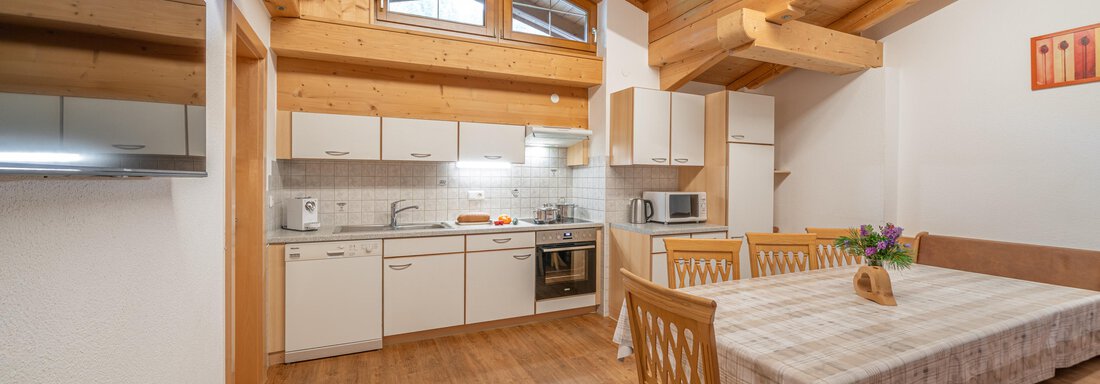 Appartement Ötztal A modern kitchen with a wooden ceiling and a large dining table. The room is bright and invitingly designed. - Haus Nicola - Sölden