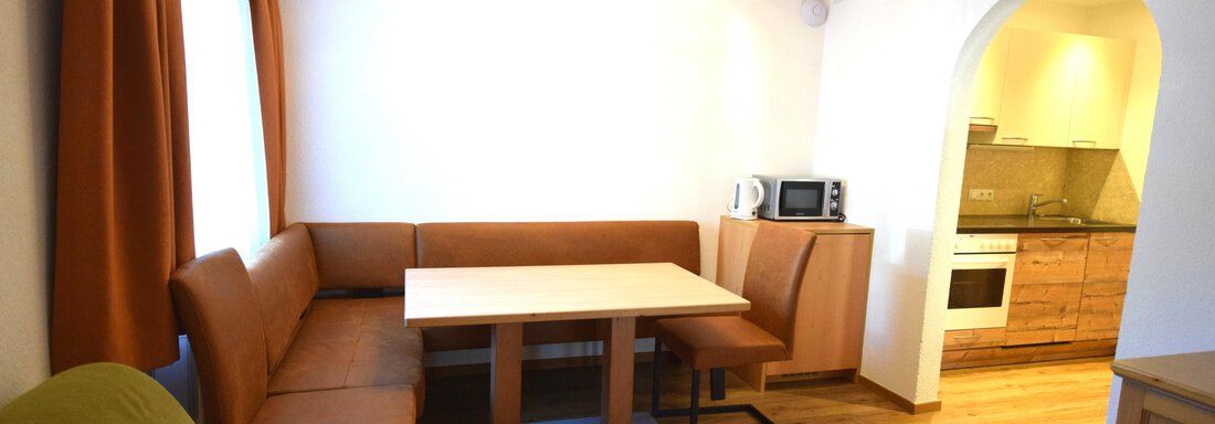 Ein gemütliches Wohnzimmer mit einem Esstisch und einer Sitzecke. Die offene Küche ist gut ausgestattet und lichtdurchflutet. - Haus Romana - Sölden