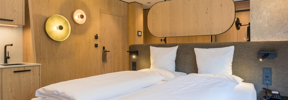 4B4A7346-HDR Ein modernes Schlafzimmer mit zwei Betten und heller Holzverkleidung. Die Einrichtung ist minimalistisch und stilvoll, ideal für eine entspannte Atmosphäre. - Hotel Alpina - Sölden